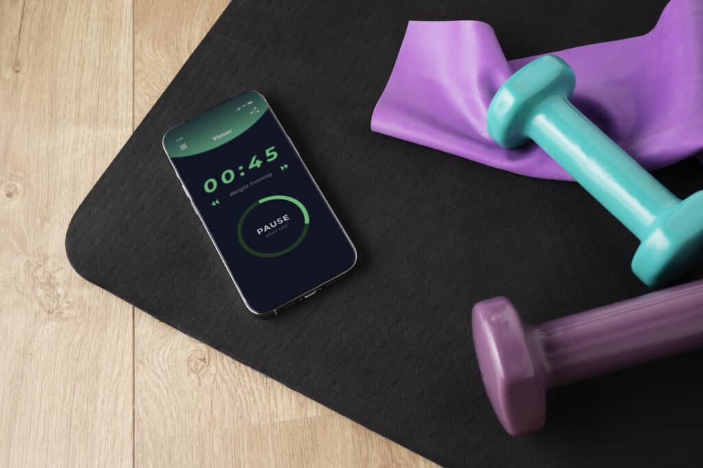 vista del telefono inteligente con pesas y colchoneta de yoga