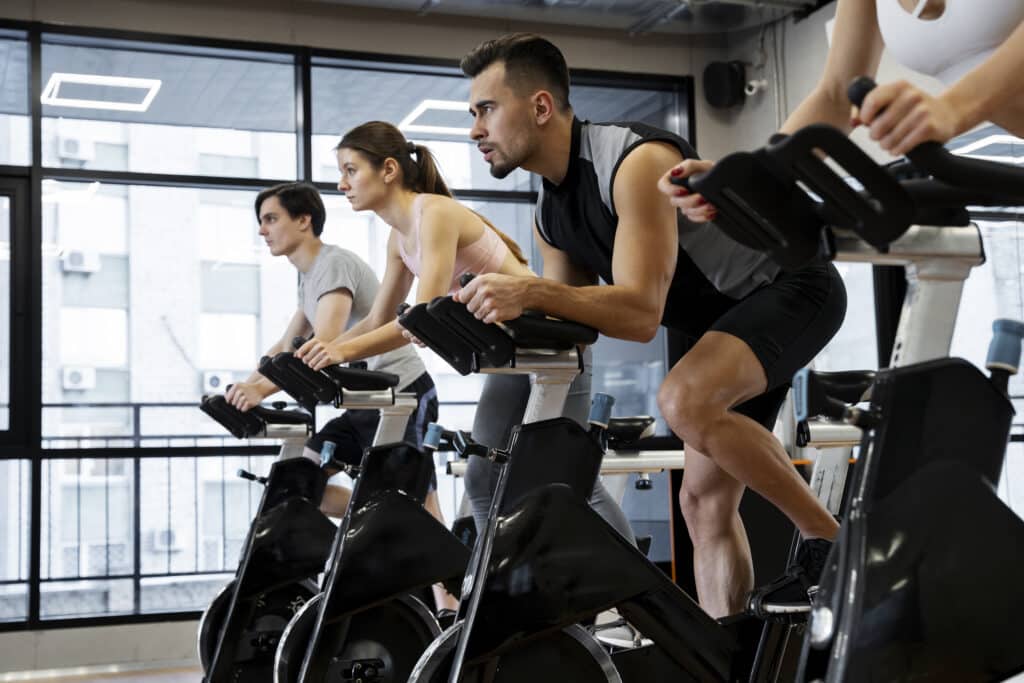 Los mejores ejercicios de cardio para principiantes: empieza a moverte y mejora tu salud 3 gente haciendo ciclismo indoor
